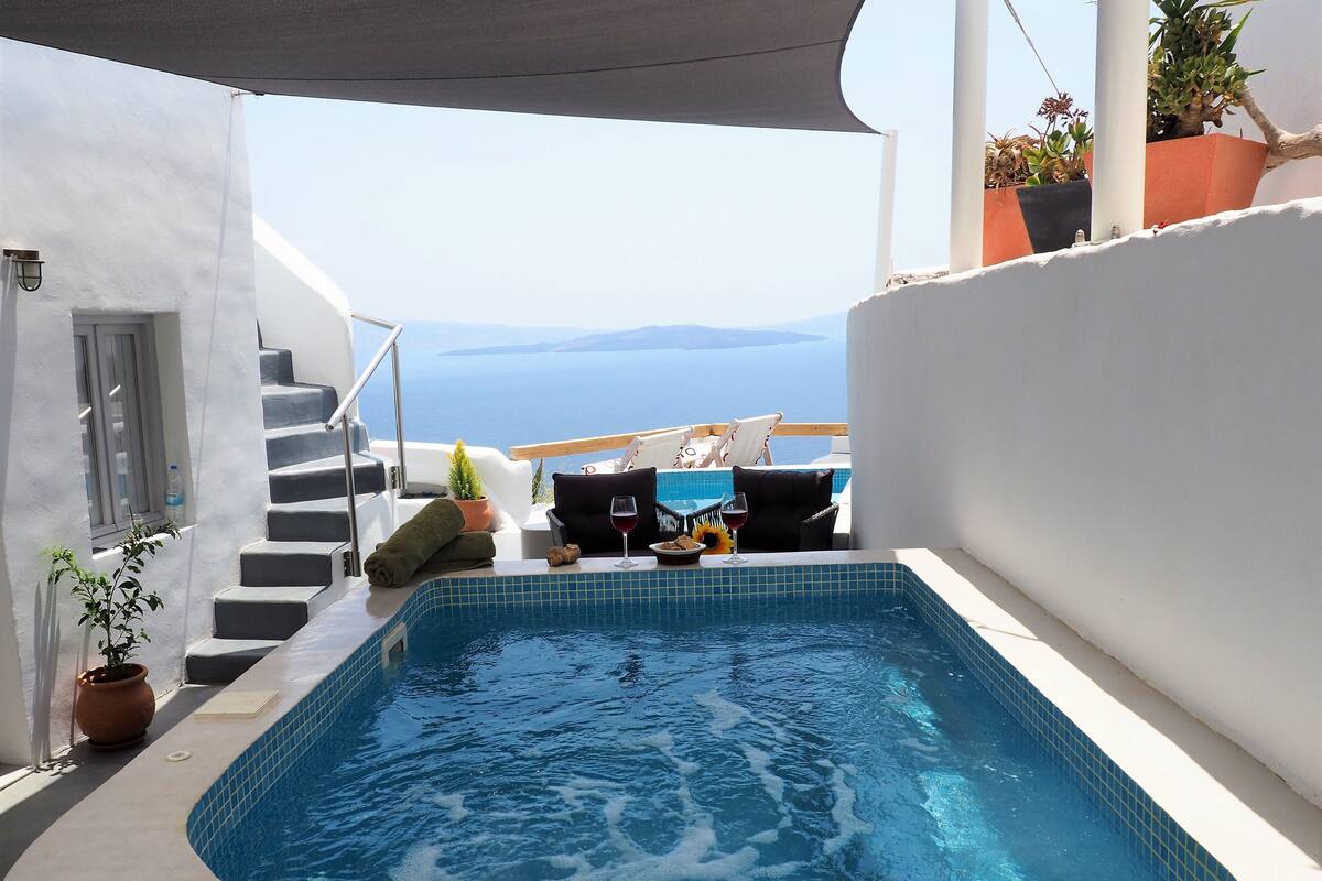 A private pool area with a view of the sea, a small table with a glass of red wine, and a chair.