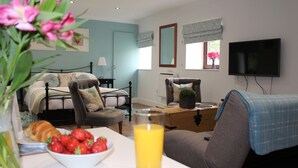 A bedroom with a bed, bedside table, and a TV. - A cute and cosy cottage, close to the train station. (dunblane)