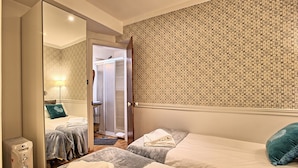 A hotel room with two beds, a large mirror, a wardrobe, and a bathroom visible through an open door. - Tv1 - Alfama Retreat | AC | 3 Bedrooms sleeps 10 walk everywhere (Lisbon)
