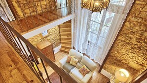 A wooden interior with a staircase, a sofa with cushions, and a small table with a lamp. - Tv1 - Alfama Retreat | AC | 3 Bedrooms sleeps 10 walk everywhere (Lisbon)