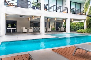 Een modern gebouw met een zwembad, terras en een balkon met planten.