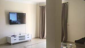 A living room with a TV mounted on the wall, a white cabinet, a glass coffee table, and a sofa. - Viviendas Vacacionales vacation rental property. 3 bedroom private pool. Value (Callao Salvaje)