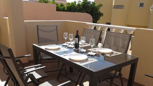 A sunlit outdoor dining area with a table set for four, including wine glasses, plates, and cutlery. - Viviendas Vacacionales vacation rental property. 3 bedroom private pool. Value (Callao Salvaje)