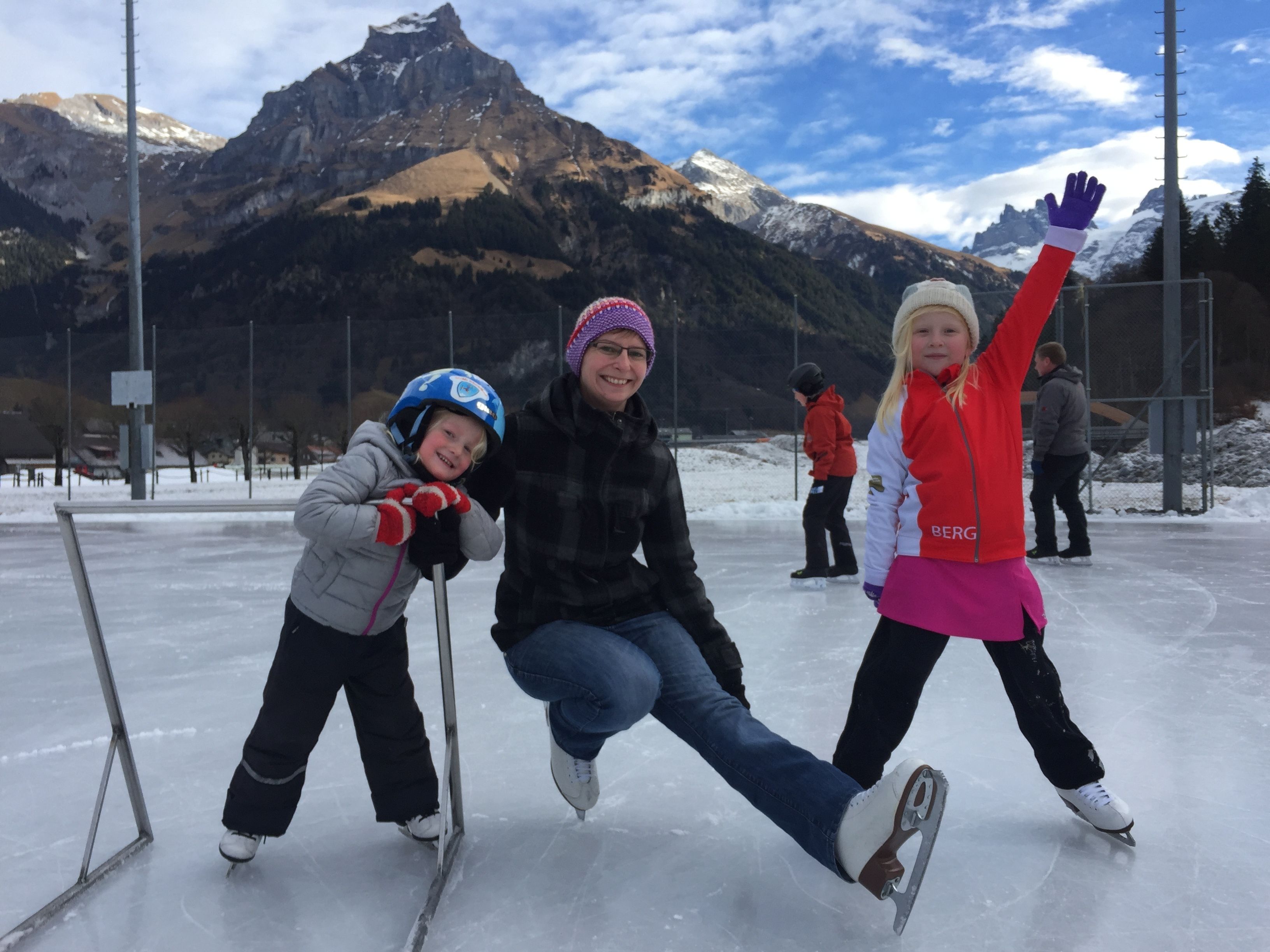 A person ice skating on a frozen surface with mountains in the background.