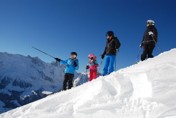 A group of skiers on a snowy mountain slope with clear blue skies and snow-covered peaks in the background. - Hotel Crystal Engelberg (Engelberg)