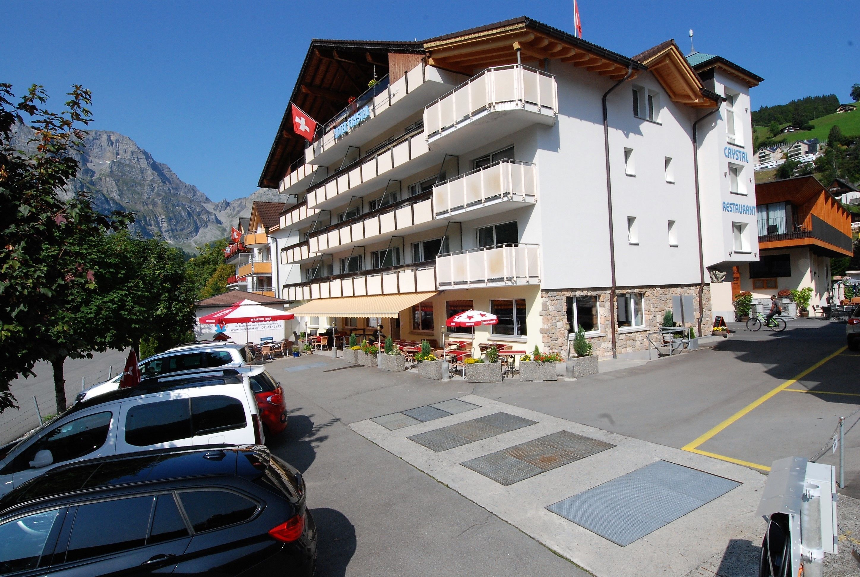Un hotel de diverses plantes amb balcons, zones d'estar a l'exterior i un paisatge de muntanya de fons.