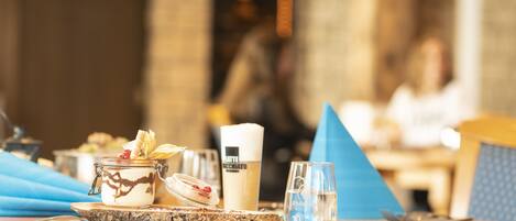A dining table with a dessert, a latte, and a glass of water.