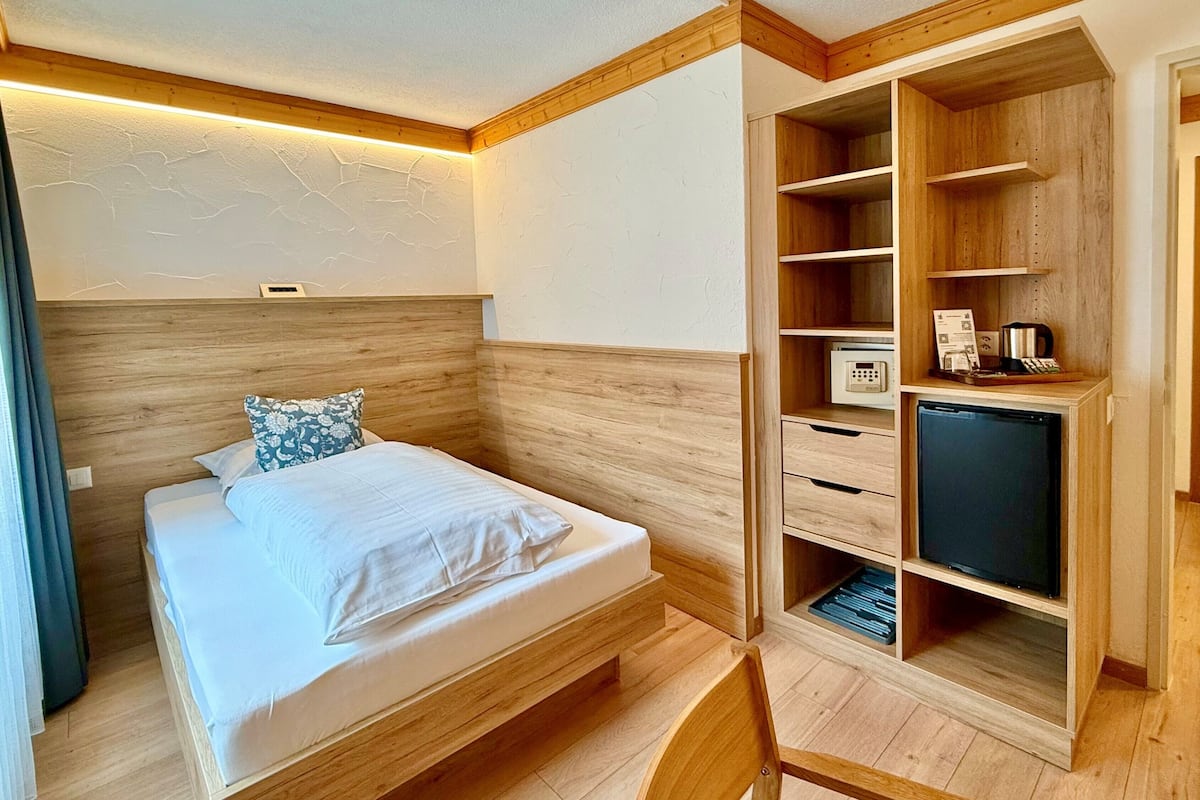Une chambre à coucher avec un lit en bois, un téléviseur encastré et une armoire en bois dotée d’étagères.