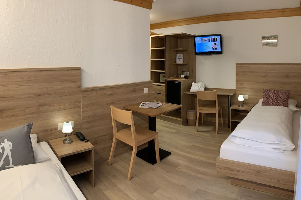 Une chambre d’hôtel comprenant un lit, un bureau avec une chaise, une télévision et une petite kitchenette.