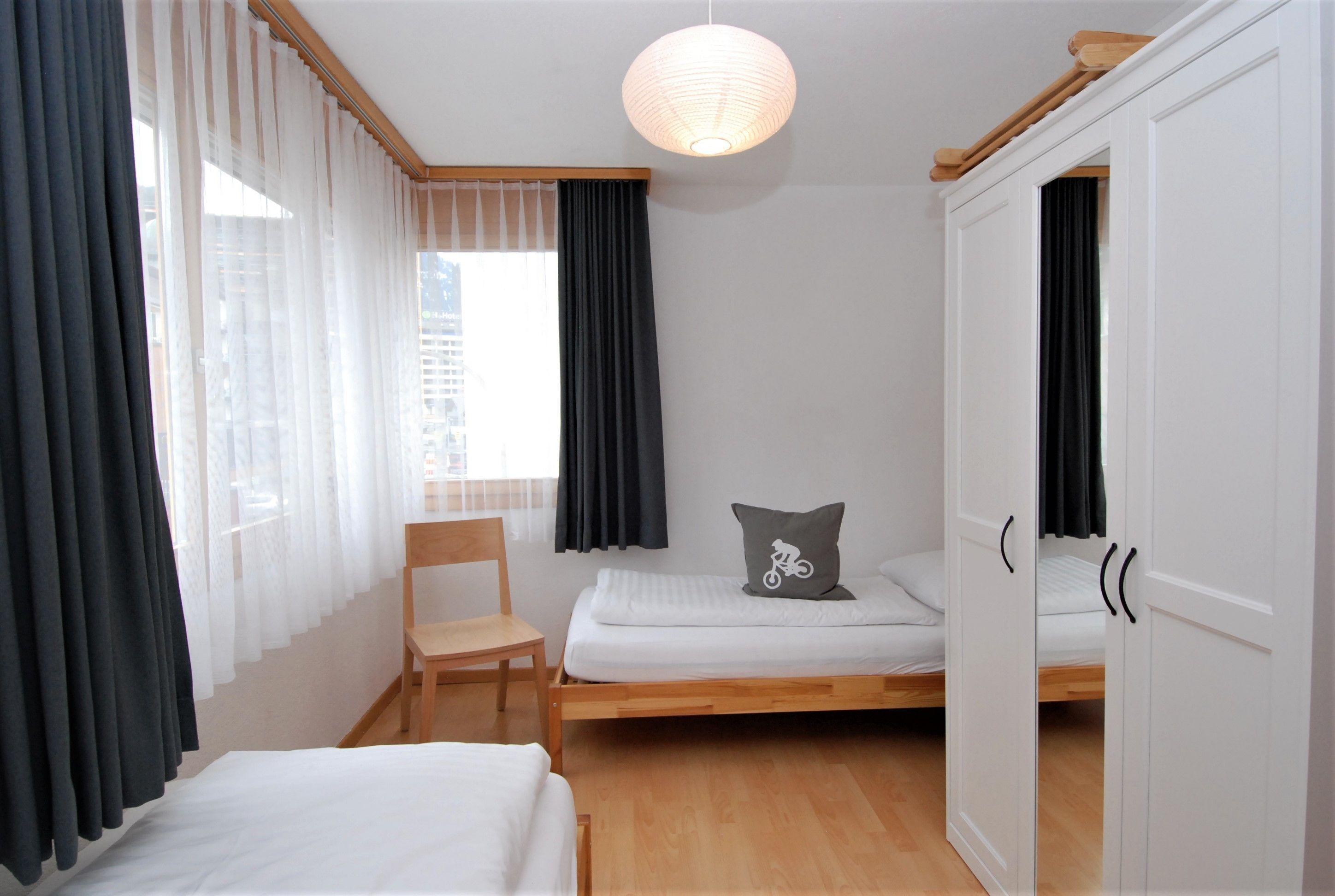A room with a bed, a chair, a small table, and a wardrobe.