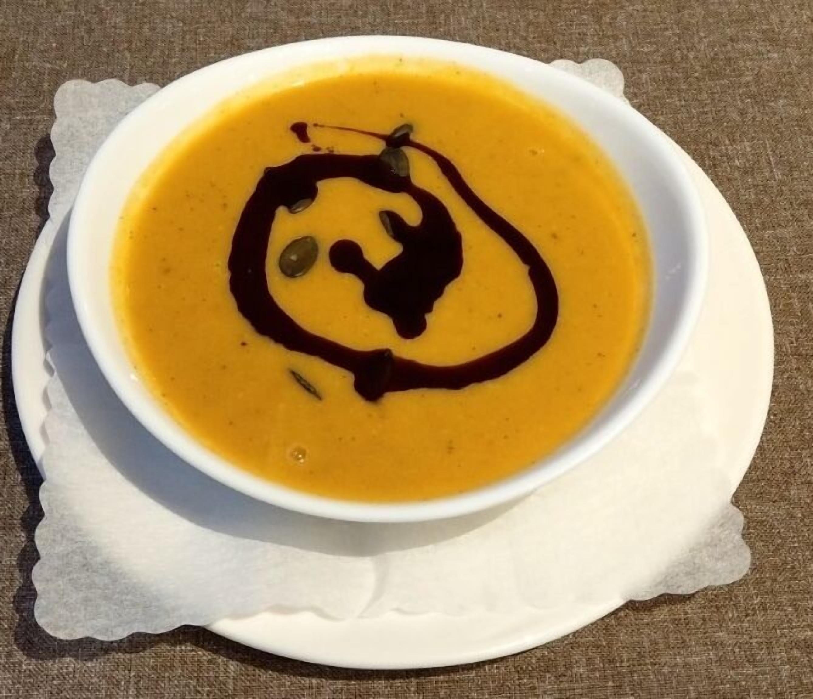Un bol de soupe, agrémenté d’une garniture, servi dans une assiette blanche.