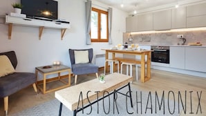 A modern living room with a sofa, a chair, a coffee table, and a TV on a shelf. - Stunning panoramic view, Cham centre, Pkg & WIFI (Chamonix-Mont-Blanc)