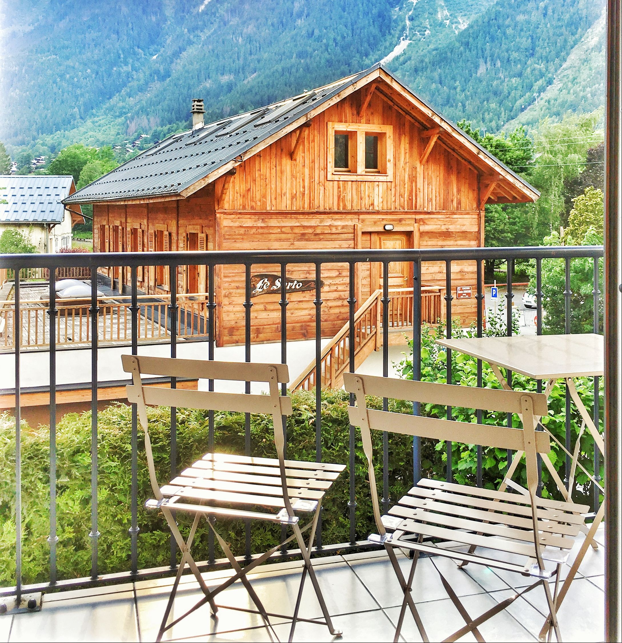 Een houten chalet met een balkon, omgeven door bergen.
