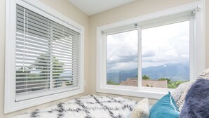 Une chambre avec une grande fenêtre, un tapis moelleux noir et blanc, et une vue sur les montagnes.