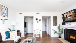 Un salon moderne doté d’une cheminée, d’un téléviseur et d’un coin salon confortable.
