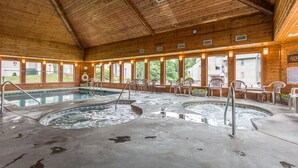 Une cabane en bois dotée de deux bains à remous et d’une piscine, entourée de chaises et de tables.