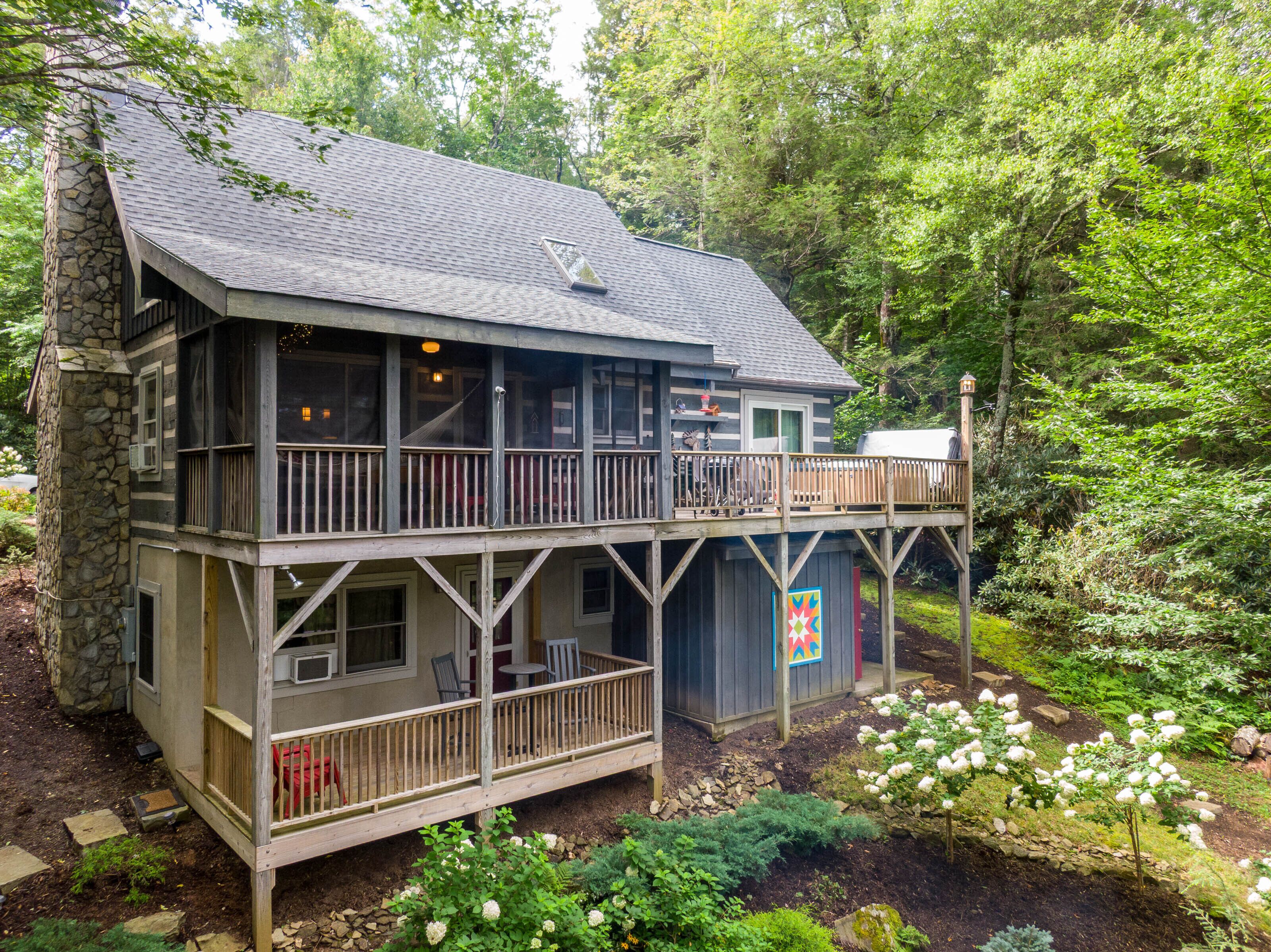 Een chalet met twee verdiepingen, een balkon, een stenen fundering en een terras met buitenmeubels.