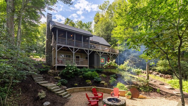 A cabin with a deck, surrounded by a garden with a fire pit and red chairs. - Scarborough Fair - Between Boone  and Banner Elk - Hot Tub - Screened In Porch - Pet Friendly (Banner Elk)
