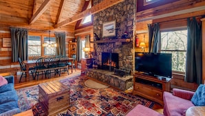 A cozy log cabin interior with a stone fireplace, wooden furniture, and a television. - Scarborough Fair - Between Boone  and Banner Elk - Hot Tub - Screened In Porch - Pet Friendly (Banner Elk)