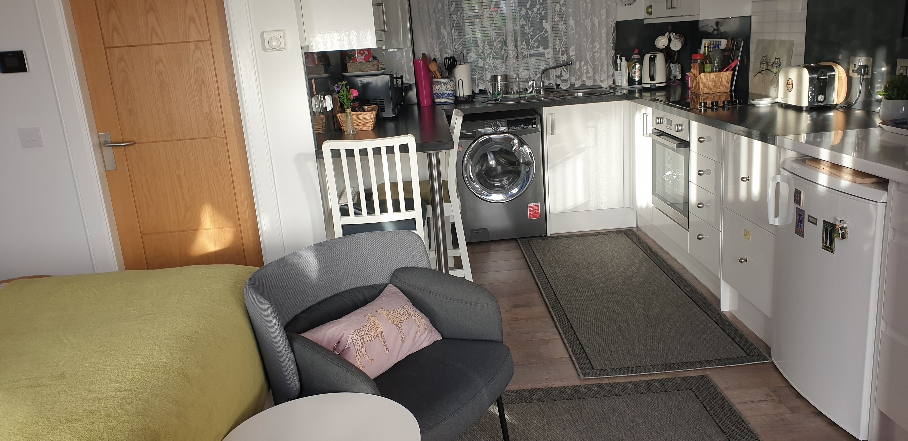 Una cocina compacta con lavadora, zona de comedor con una silla y una mesa pequeña.