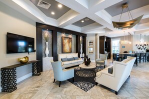 A modern living room with a sofa, armchairs, a coffee table, and a TV mounted on the wall. - Brand New Modern Pool Home With Designer Furniture Package- Must See Pics!!! (Davenport)