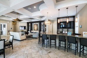 A modern kitchen with a bar area, a seating area, and a flat-screen TV. - Brand New Modern Pool Home With Designer Furniture Package- Must See Pics!!! (Davenport)