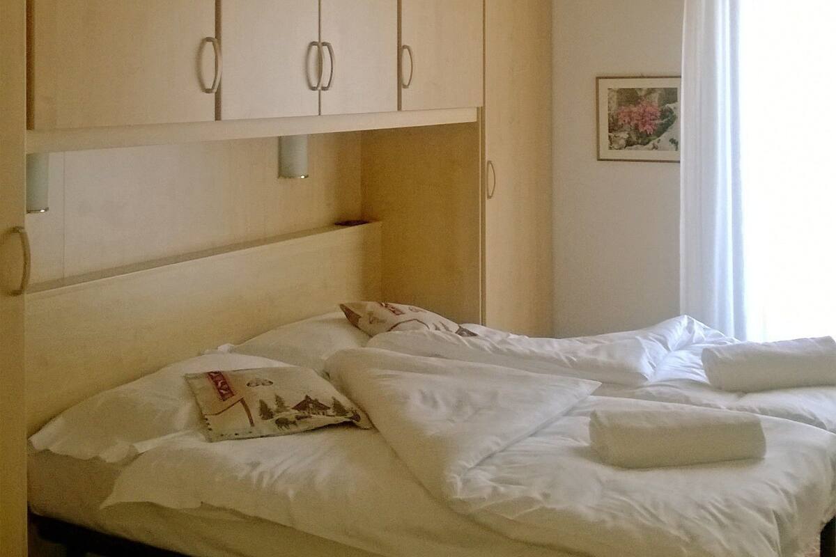 A bedroom with a wooden ceiling, a bed with white linens, and a small bedside table.