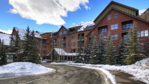 Un chalet à étages, à l’extérieur rouge et doté de nombreuses fenêtres, entouré d’un paysage enneigé et d’arbres.