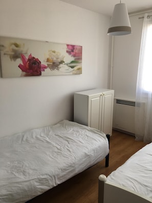 A bedroom with a single bed, a white wardrobe, and a wall-mounted air conditioning unit.