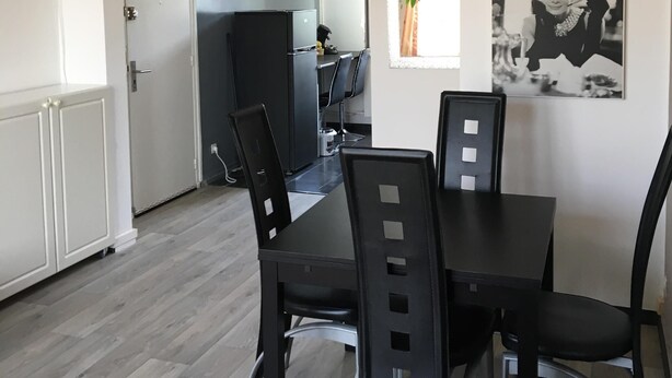 A modern dining area with a black table and chairs, a white ceiling, and a black-framed picture on the wall. - T3 ROUEN docks side with free parking - 4 BEDS (ROUEN)
