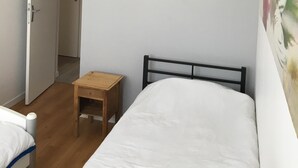 A bedroom with a bed, a wooden nightstand, a white lamp, and a door leading to another room. - T3 ROUEN docks side with free parking - 4 BEDS (ROUEN)