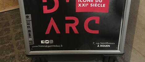 A poster with text and a graphic, likely for an event or exhibition, displayed on a stand.