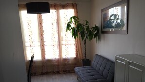 A living room with a sofa, a potted plant, a cabinet, and a painting on the wall. - T3 ROUEN docks side with free parking - 4 BEDS (ROUEN)