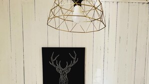 A bedroom with a bed, a nightstand, a lamp, and a wall-mounted geometric light fixture.