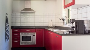 A kitchen with red cabinets, a microwave, a coffee maker, and a sink.