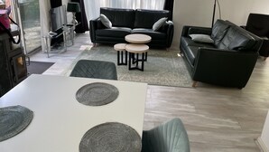 A modern living room with a sofa, two round tables, and a dining table.