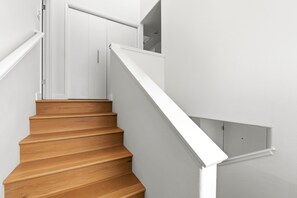 A wooden staircase with white handrails and a white wall. - Tides In - Monterey Beach House - Oceanfront, Walk to Fisherman's Wharf (Monterey)
