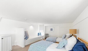A bedroom with a bed, bedside table, lamp, and a window with blinds. - Tides In - Monterey Beach House - Oceanfront, Walk to Fisherman's Wharf (Monterey)
