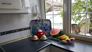 Una cucina con un piano di lavoro, un bollitore, tazze, un'anguria e banane.