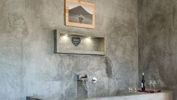 Relax in a serene space with a bathtub, wine and glasses, and a framed photograph.