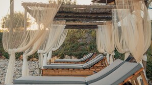 A wooden pergola with white drapes and multiple lounge chairs. - Monte Gois Country House e Spa (Almodôvar)