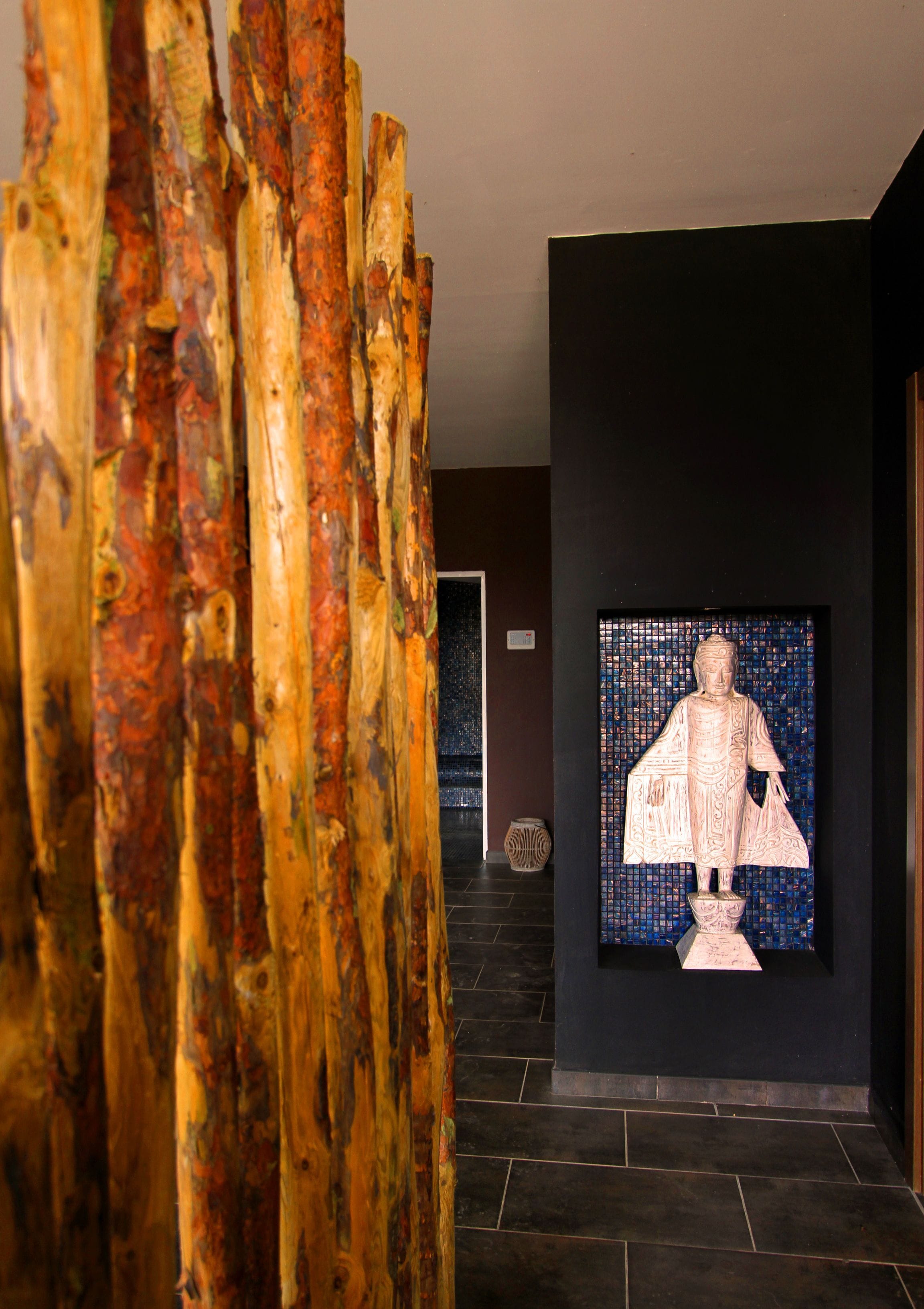 A hallway with a wooden sculpture and a mosaic statue.