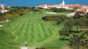 Um campo de golfe com vista para o oceano e edifícios à beira-mar.