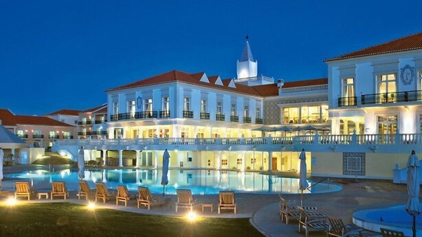Um hotel grande com várias varandas, piscina e áreas de estar ao ar livre.