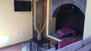 Un salón acogedor con una chimenea de piedra, un televisor de pantalla plana montado en la pared y una alfombra con estampado de cebra.