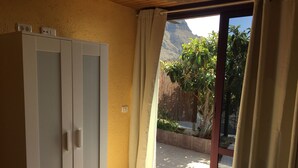 Habitación con cama, armario y puerta corrediza de vidrio que da a un espacio exterior con vistas a la montaña.