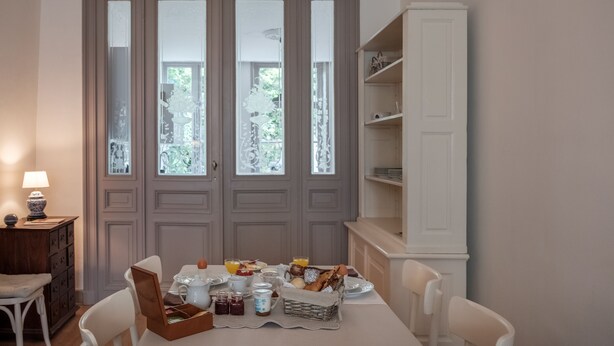 A dining area with a table set for breakfast, including bread, fruit, and beverages. - Braamberg Bed & Breakfast (Bruges)