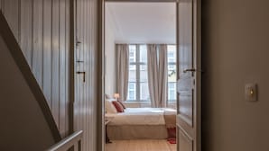 A narrow hallway leading to a bedroom with a bed, a window, and a door. - Braamberg Bed & Breakfast (Bruges)