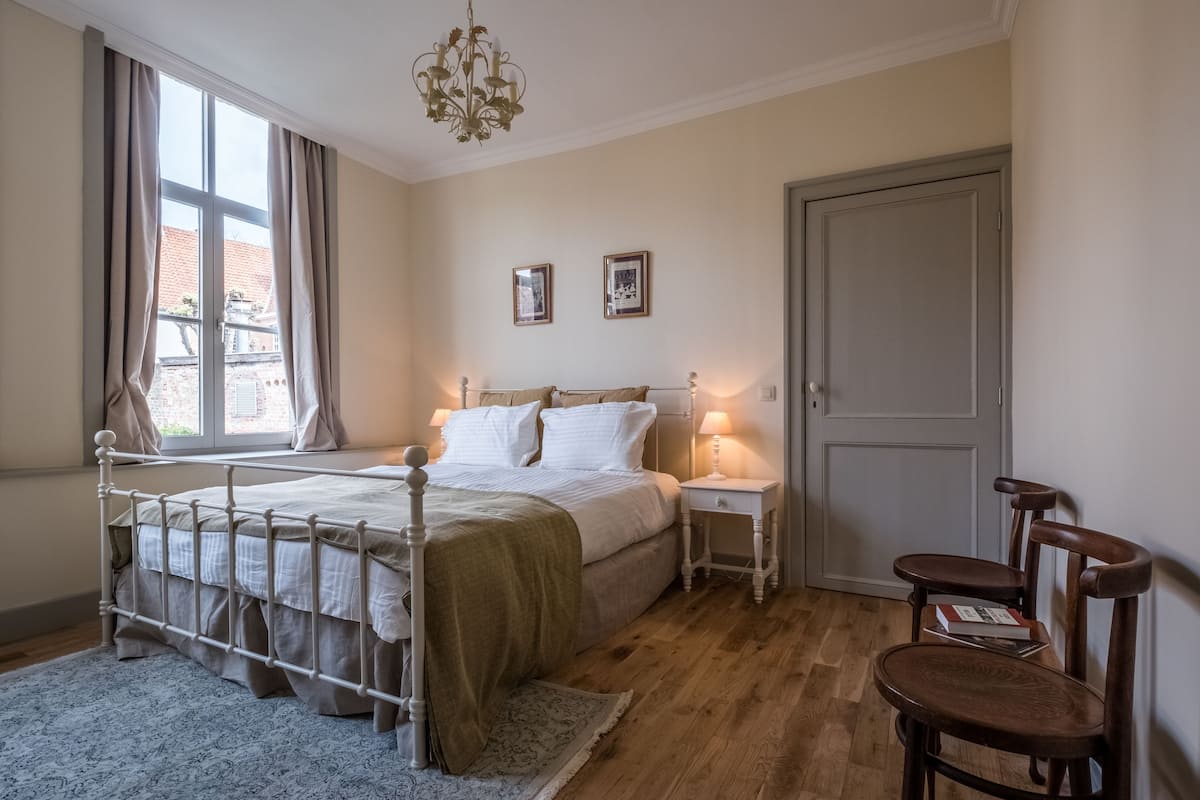 A bedroom with a bed, bedside tables, a chair, and a door.