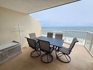 A balcony with a table and chairs, overlooking a beach.
